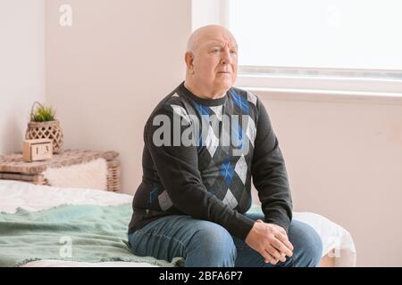 Älterer Mann, der zu Hause an geistiger Behinderung leidet Stockfoto