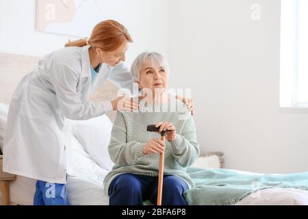 Ältere Frau mit geistiger Behinderung und Arzt zu Hause Stockfoto