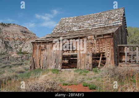 Alte Holzbarn: Eine Scheune mit fehlenden Schindeln und Seitenbrettern wittert im Sonnenschein des südlichen Utah. Stockfoto