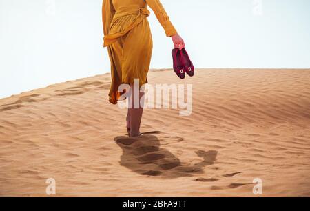 Frau, die in einer Wüste an einem sonnigen Tag geht, um den Blick aus dem unteren Winkel zu genießen Stockfoto