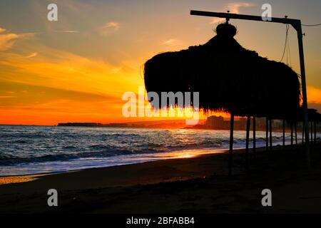 Toller Sonnenuntergang am Strand mit unglaublich glitzernden Wellen. Sonnenuntergang und Wellen am spektakulären Strand. Blau und Gelb unendlich Stockfoto