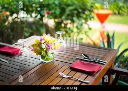 Farbenfrohes, wunderschönes Orchideen-Bouquet-Dekor in Glasvase, eingerichtet auf einem Holz-Esstisch in Indien, Empfang für Hochzeitsfeiern. Stockfoto