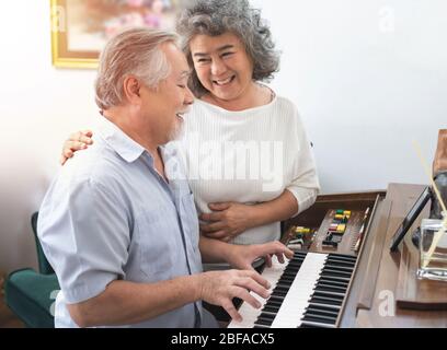 Ältere ältere ältere Mann spielt Klavier im Pflegeheim gehört von älteren Frau, Retreatment ältere asiatische Großmutter und Großvater spielen Klavier zu Hause Stockfoto