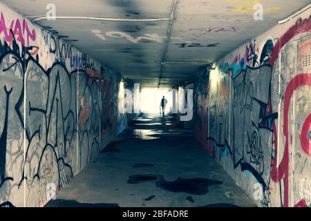 Geheimnisvolles Licht am Ende des Tunnels. Flucht und Ausgang zu Freiheit und Hoffnung Konzept. Dunkler und langer unterirdischer Gang mit Licht. Silhouette eines Jungen Stockfoto