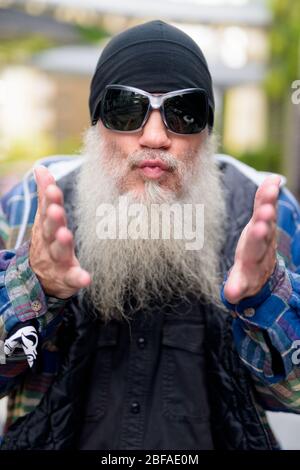 Gesicht der reifen bärtigen Mann mit Sonnenbrille weht Kuss im Freien Stockfoto