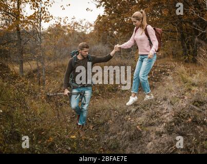 Mann Unterstützt Frau, Um Den Hügel Hinunter Im Freien Zu Gehen Stockfoto