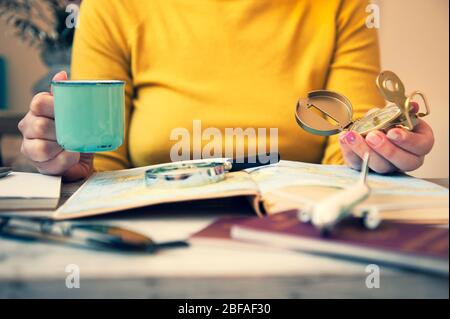 Junge Frau trinkt Kaffee und plant Weltreise mit Reisekarte. Backpacker Mädchen auf der Suche nach neuen Ländern zu erkunden. Reisetrends, Weltenbummler Stockfoto