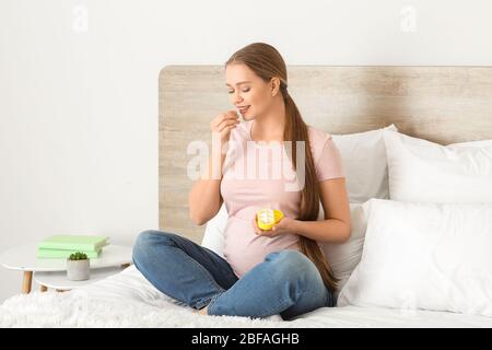 Junge schwangere Frau, die Pille zu Hause nimmt Stockfoto