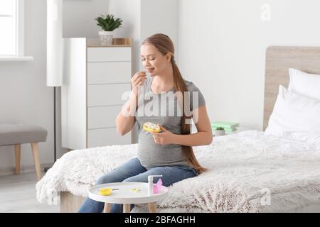 Junge schwangere Frau, die Pille zu Hause nimmt Stockfoto