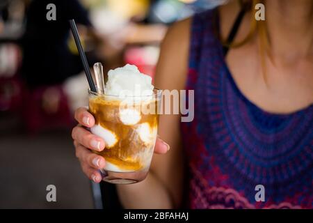 Ein Glas traditionellen vietnamesischen Kokoseis Kaffee in Frauenhand. Bild von beliebten Café von Vietnam in Hoi an. Stockfoto