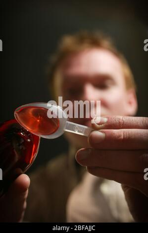 Mann gießt Hustenmischung auf einen Plastiklöffel Stockfoto