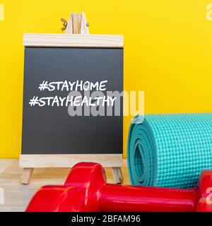 Gesund bleiben während des Aufenthalts zu Hause Auftragskonzept - Tafel, Hantel und Yoga-Matte. Stockfoto