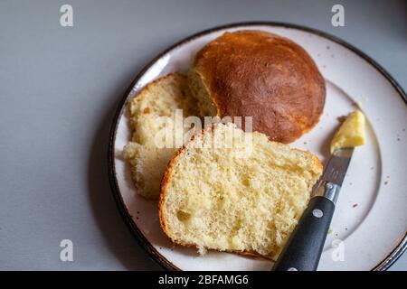 Hausgemachte Brötchen auf Teller mit Butter & Messer.Hausmannskost.Hobby, Zeitvertreib. Stockfoto