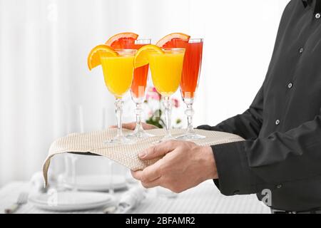 Kellner mit Gläsern leckeren Mimosa-Cocktail auf dem Tablett beim Bankett Stockfoto