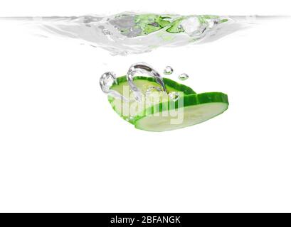 Fallen von frischen Gurkenscheiben in Wasser vor weißem Hintergrund Stockfoto