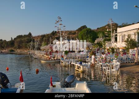 Restaurant und Bougainvillea Blumen am Strand in Gumusluk, Bodrum. Farbenfrohe Stühle, Tische und Blumen in der Stadt Bodrum in der Nähe der schönen ääischen See. Stockfoto