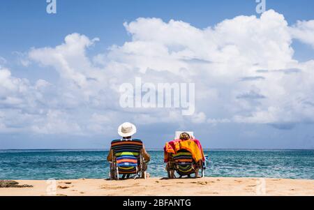 Ein Paar sitzt auf einem Strand in ihren Stühlen und entspannt sich in der Sonne. Moloa a Bay Beach, Kauai, Hawaii, USA. Stockfoto