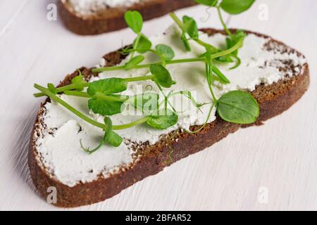 Gesundes makrobiotisches Frühstück. Sandwich mit Frischkäse und Erbsen-Microgreens Stockfoto