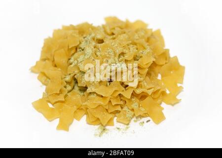 Trenetta mit Pesto. Gelbe Pasta harte Sorten mit trockenem Pulver aus Basilikum und Käse. Trockene Pasta Trenetta mit Pesto auf weißem Hintergrund Draufsicht. Stockfoto