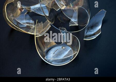 Zerbrochene Tasse auf schwarzem Hintergrund. Becher mit doppeltem Boden transparente Scherben. Zerbrochenes Glas von den Küchenutensilien. Gefahr des Zerschneidens von Scherben. Stockfoto