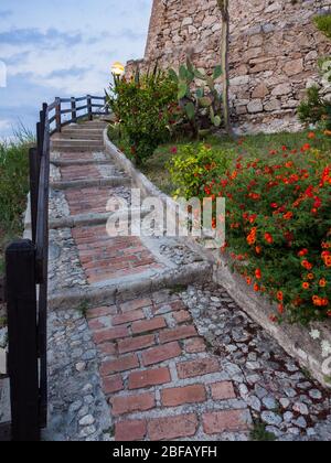 Fußgängerweg führt zu einem alten Steinwachturm. Stockfoto