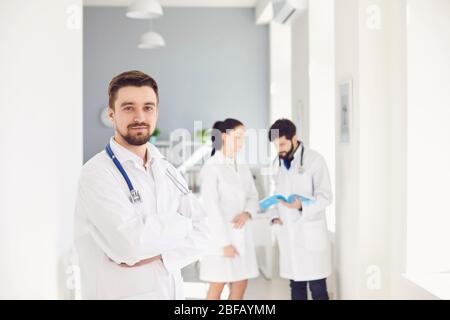 Ein Praktizierender Arzt mit Stethoskop vor dem Hintergrund eines Arztes in der Klinik. Stockfoto