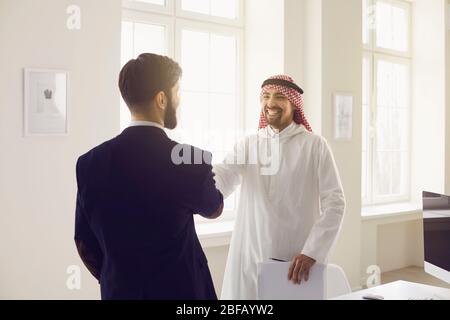 Handschlag arabischer und europäischer Geschäftsleute im Büro. Stockfoto