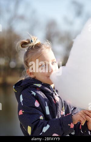 Nettes kleines Mädchen essen Zuckerwatte. Glückliche Kindheit und Kinder Emotionen Stockfoto