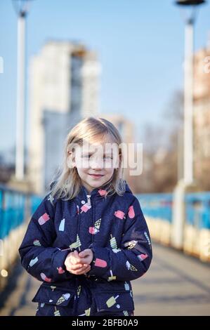 Fröhliches Kind in blauem Jakett posiert im Freien. Kaukasische junge Mädchen genießt eine helle Frühling Lebensstil Stockfoto