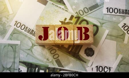 Job Word in Holzwürfel geschrieben auf 100 Euro Banknoten. Arbeit Fähigkeiten Gehalt Lohn freiberufliche Konzept Stockfoto