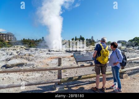 Rotorua, Neuseeland. Paar vor dem Geysir Pōhutu, Te Puia, Geothermales Tal Te Whakarewarewa, Rotorua, Nordinsel, Neuseeland Stockfoto