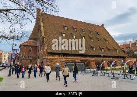 Danzig, Polen, 15. April 2018: Die Menschen gehen in der Nähe der großen Wassermühle Wielki Mlyn mit Ziegeldach in der Nähe Radunia Kanal in der historischen Altstadt Stockfoto