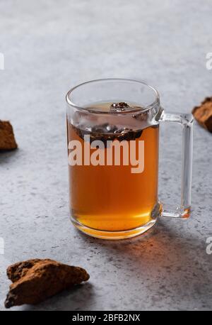 Bio Chaga Tee in der Tasse. Trendige russische, gesunde Infusion aus Birkenpilz auf hellem Hintergrund. Nahaufnahme. Vertikal Stockfoto