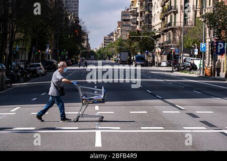 Ein Mann überquert die verlassene Aragón Straße und schiebt während der Haft einen Supermarkt-Wagen.Barcelona überwindet einen Monat der häuslichen Eingrenzung und sozialen Distanz. Es ist bereits 34 Tage her, seit der 15. März, als die spanische Regierung einen Ausnahmezustand verordnete. Nur wesentliche Dienste funktionieren. Stockfoto