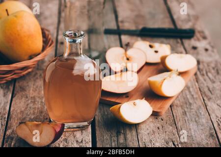 Apfel Bio-Essig in Glaskrug mit reifen frischen Äpfeln auf Holztisch. Gesunde Bio-Lebensmittel. Selektiver Fokus Stockfoto