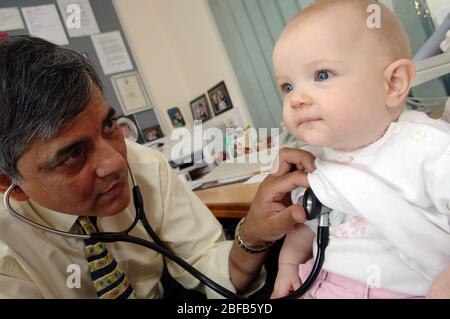 Ein Hausarzt hört den Herzschlag eines Babys mit einem Stethoskop (Modell veröffentlicht) Stockfoto