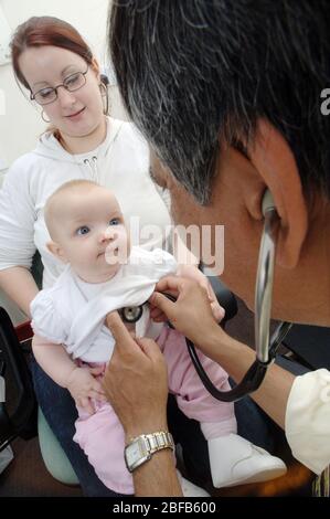 Ein Hausarzt hört den Herzschlag eines Babys mit einem Stethoskop (Modell veröffentlicht) Stockfoto