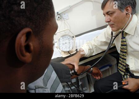 Ein Hausarzt überprüft den Blutdruck eines Patienten mit einem Blutdruckmessgerät (Modell freigegeben) Stockfoto