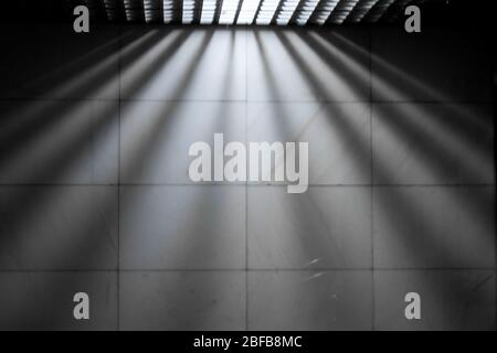 Glanz. Die Lichtstrahlen des Gittes in der Decke fallen herunter und weichen mit symmetrischen Strahlen entlang der Wand. Strahlen erzeugen Rhythmus und Symmetrie i Stockfoto