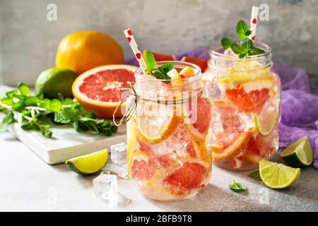 Erfrischendes Getränk aus Eis. Mason Becher gefüllt mit frischem Mojito Cocktail mit Grapefruit, Limette und Minze auf einem Hintergrund aus grauem Stein. Stockfoto