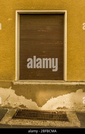 Alte Fassade mit braunen Holzfenstern und Schacht für Kellerfenster Stockfoto