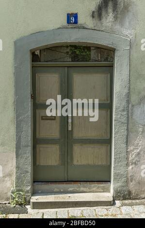 Grüne Holztür mit Kassetten in alten Wänden mit schrägen Wänden Stockfoto