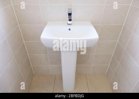 Ein weißes Waschbecken, das neben einer gefliesten Wand sitzt Stockfoto