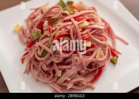 Herzhafter Wurstsalat mit Käsebreifen und Gurken Stockfoto