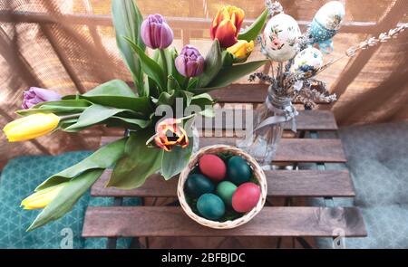 Balkontisch aus Holz mit Ostereiern und Tulpenblüten-Vase bedeckt Stockfoto
