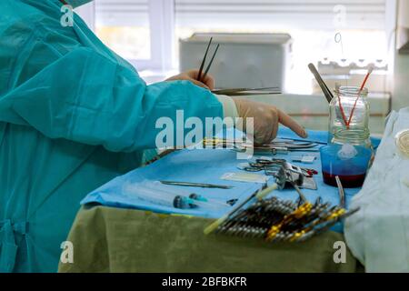 Nahaufnahme der Scheuernschwester, die medizinische Instrumente für die Operation im Operationssaal nimmt Stockfoto