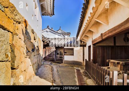 Alte weiße Burg in Japan bei Osaka - Himeji. Innenhof und Gehweg zwischen alten historischen Gebäuden und Steinmauern. Stockfoto