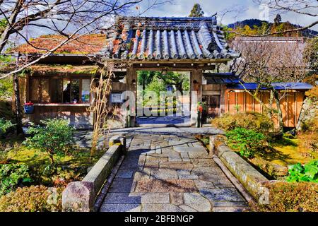 Traditioneller japanischer Garten durch offenes historisches Tor mit Dachbalken und Fliesen im alten ländlichen Dorf Ohara in der Nähe von Kyoto. Stockfoto