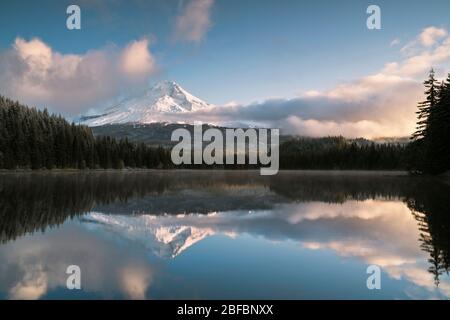 Am frühen Morgen brechen Wolken auf und offenbaren den frischen Herbstschnee auf dem Mt Hood in Oregon, der sich in Trillium Lake spiegelt. Stockfoto