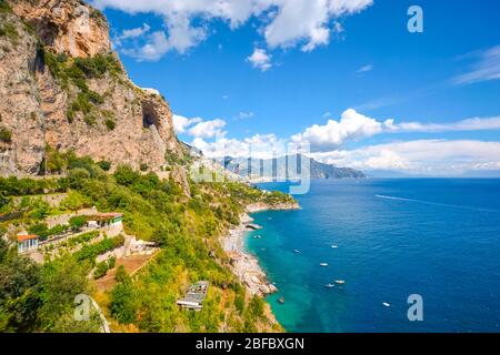 Die Amalfiküste in der Nähe von Positano und Sorrento an einem Sommernachmittag mit Booten im Wasser, einem Sandstrand und Häusern und Resorts am Hang Stockfoto